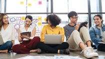 Group of young happy creative business people using electronic devices tablet and laptop connection together in modern office.